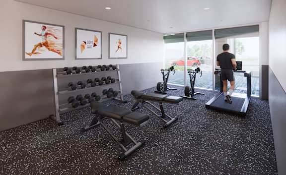 A man is working out in a gym with a row of dumbbells and a treadmill.