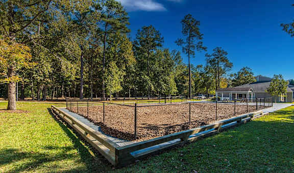 A baseball field with a fence and trees in the background.