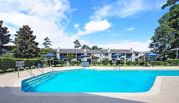 A large blue swimming pool in front of a building with trees in the background.