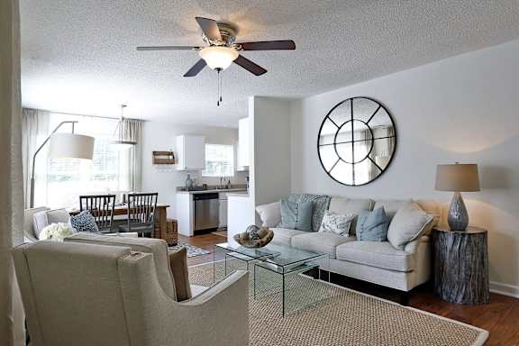 A living room with a white couch and a glass coffee table.