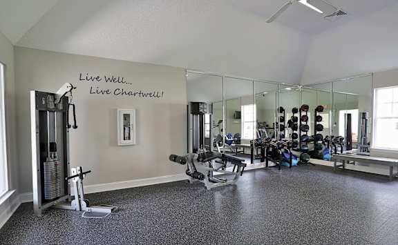 A gym with a mirrored wall and a motivational quote.