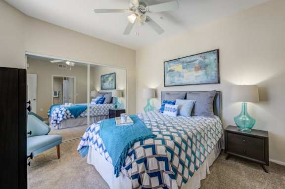 A bedroom with two beds and a ceiling fan.