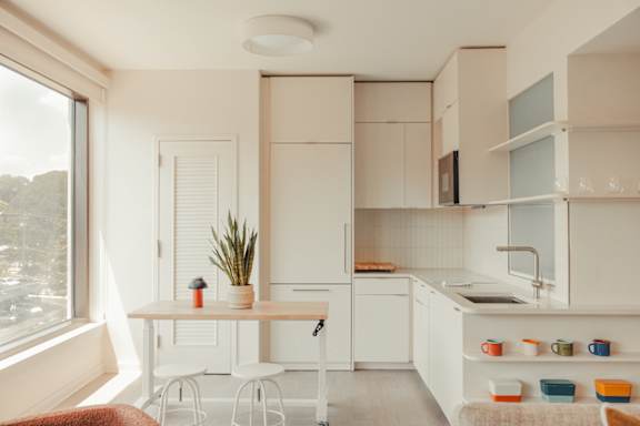 a small kitchen with white cabinets and a table and chairs at Scout Living, powered by Placemakr Apartments, Atlanta, GA, 30308
