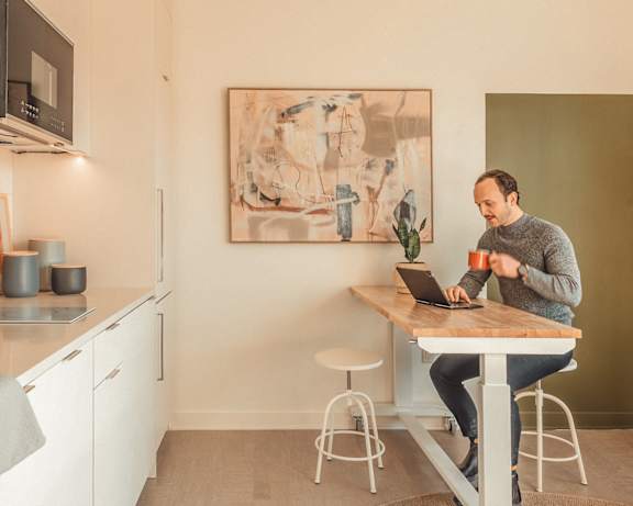 a man sitting at a kitchen table using a laptop computer at Scout Living, powered by Placemakr Apartments, Atlanta