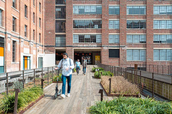 people walking on a boardwalk in front of a building at Scout Living, powered by Placemakr Apartments, Atlanta, Georgia