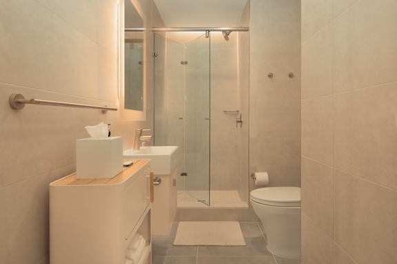a white bathroom with a shower and a toilet at Scout Living, powered by Placemakr Apartments, Georgia