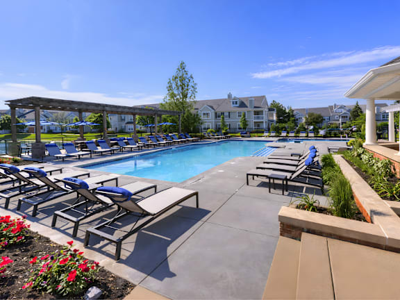 A pool surrounded by lounge chairs and flowers.