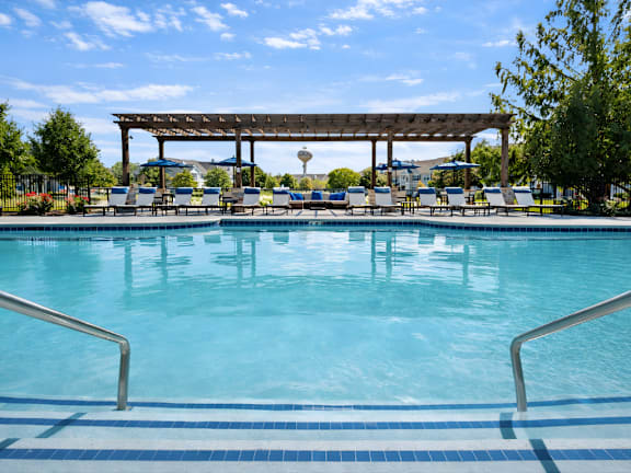 A large swimming pool with a wooden pergola over it.