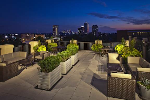 A rooftop patio with a view of the city at dusk.