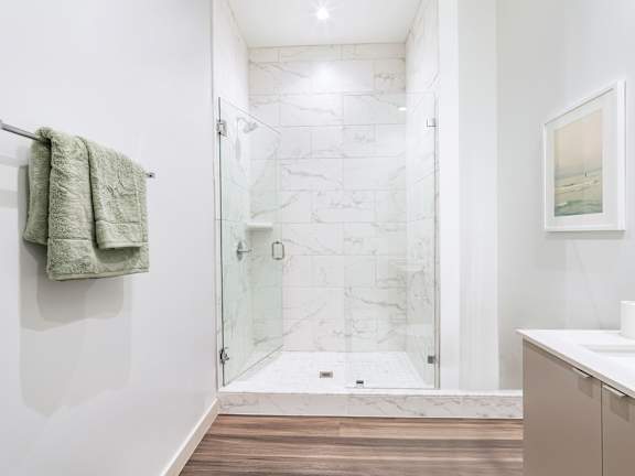 A bathroom with a walk-in shower and a towel hanging on the wall.
