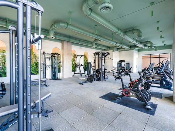 A gym with a variety of equipment including treadmills, weights, and exercise machines.