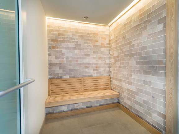 A wooden bench sits against a brick wall in a room.