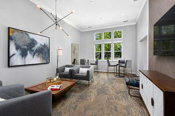 A living room with a grey couch and a painting on the wall.