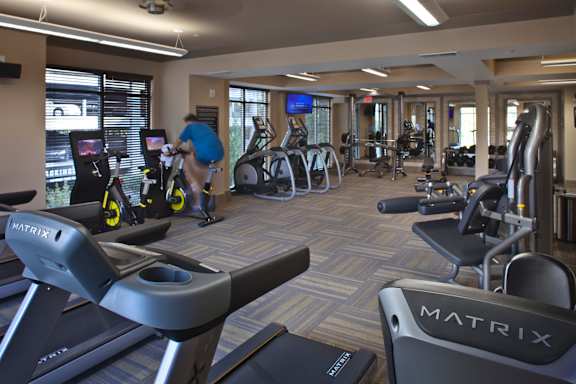 A gym with a variety of equipment including treadmills, stationary bikes, and weight machines.