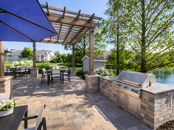 A patio with a grill and a table under a blue canopy.