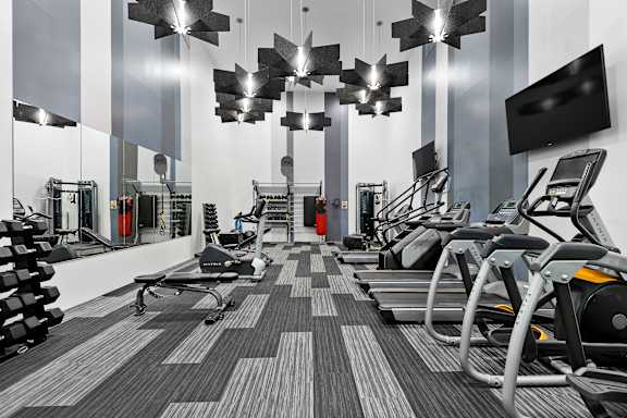 A gym with treadmills, exercise bikes, and mirrors.