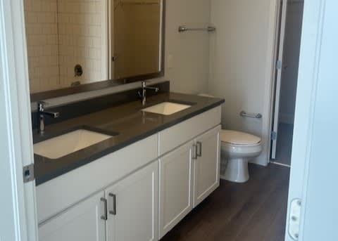 A bathroom with a toilet, sink, and mirror.