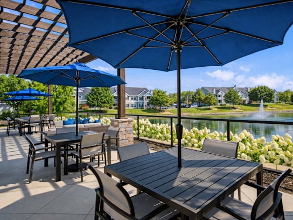A patio with tables and chairs under blue umbrellas.
