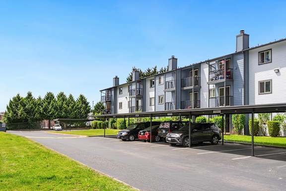 a parking lot with cars in front of an apartment building at Eagles Landing Apartments, Everett, WA