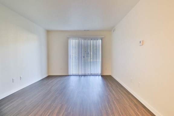 A room with wooden flooring and a window with blinds.