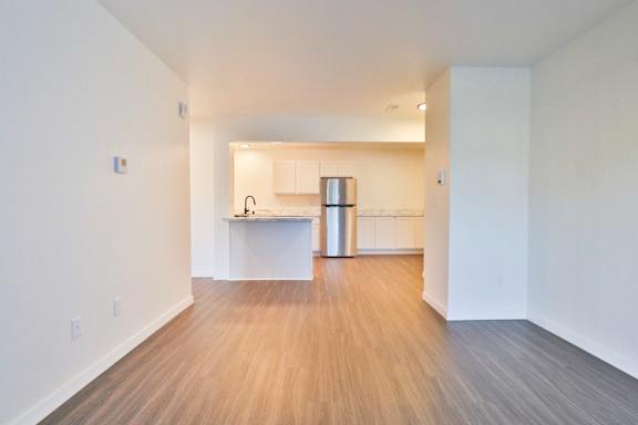 A kitchen with white cabinets and a wooden floor.