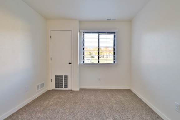 A room with a door, window, and carpeted floor.