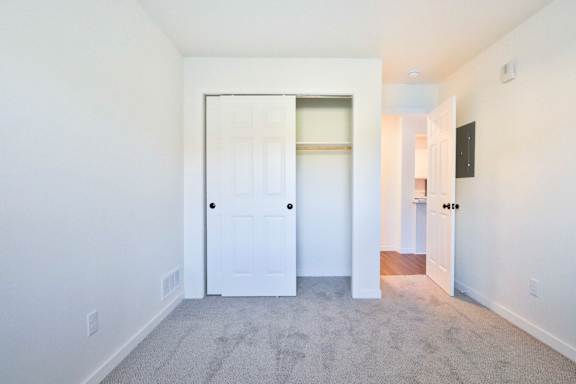 A white door is in a white room with a grey carpet.