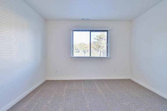 A room with a window and carpeted floor.