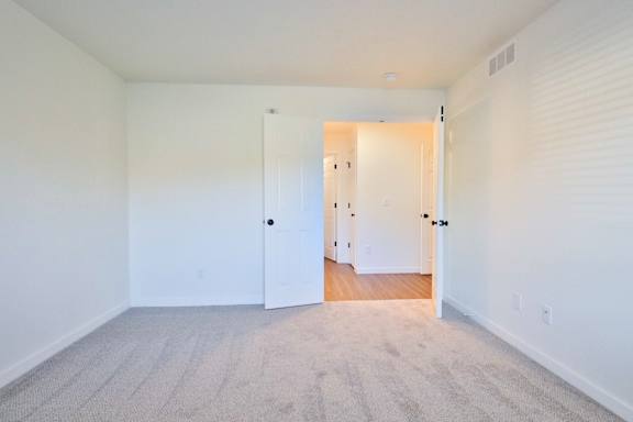 A room with a carpeted floor and a white door.