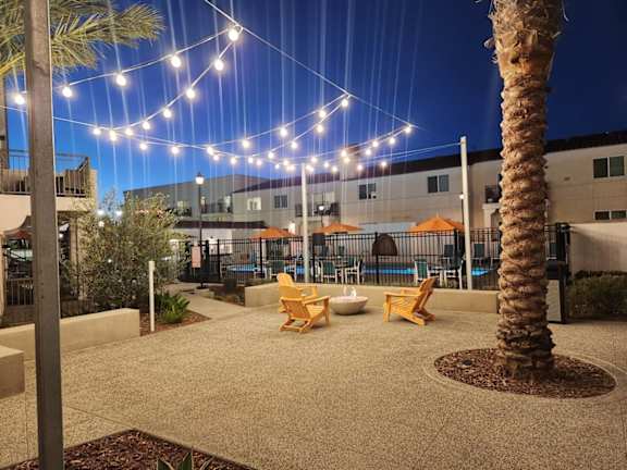 A palm tree is in the foreground of a lit up patio area.