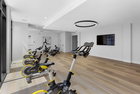 a gym with rows of exercise bikes and a tv on the wall