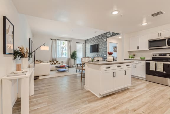 a white and black kitchen and living room with a table at The Venue at Orange Apartments, Redlands, California