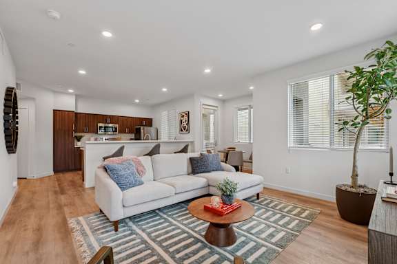 Living room in a 2-bedroom Park apartment with wood flooring, and open-layout leading to dining nook and kitchen