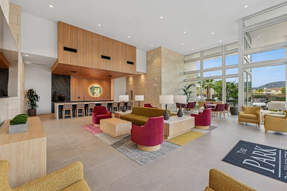 Community clubhouse at the Park with plenty of lounge seating, dining tables, and an oversized island facing kitchenette.