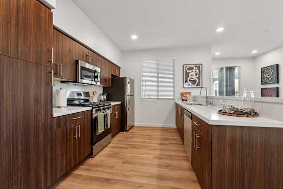 A modern kitchen with dark wood cabinets and stainless steel appliances.