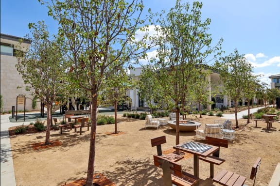 a courtyard with benches and trees and a building in the background at The Max on Jefferson Apartments, Murrieta, California