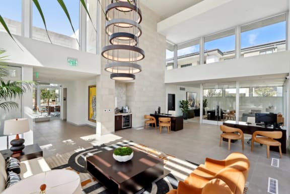 a living room with a large amount of windows and a table and chairs at The Max on Jefferson Apartments, Murrieta