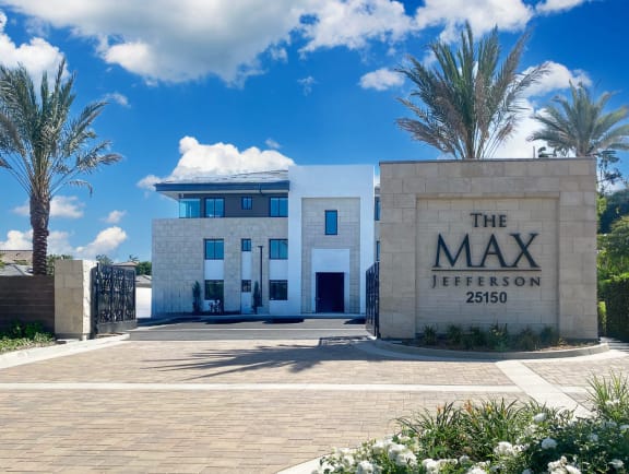 a large building with palm trees in front of it at The Max on Jefferson Apartments, California