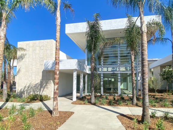 a building with palm trees in front of it at The Max on Jefferson Apartments, Murrieta
