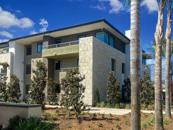 a large white house with palm trees in front of it at The Max on Jefferson Apartments, California, 92562