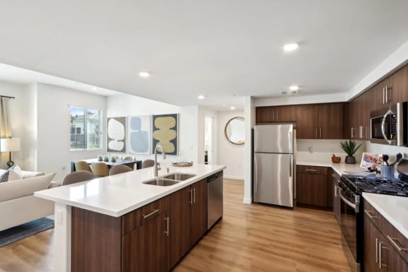 a kitchen and living room with a white counter top and a stainless steel refrigerator at The Max on Jefferson Apartments, California, 92562