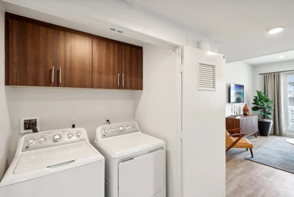 a washer and dryer in a laundry room with a living room at The Max on Jefferson Apartments, Murrieta, 92562