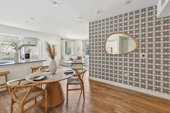 a dining room with a table and chairs and a mirror at The Venue at Orange Apartments, Redlands, CA