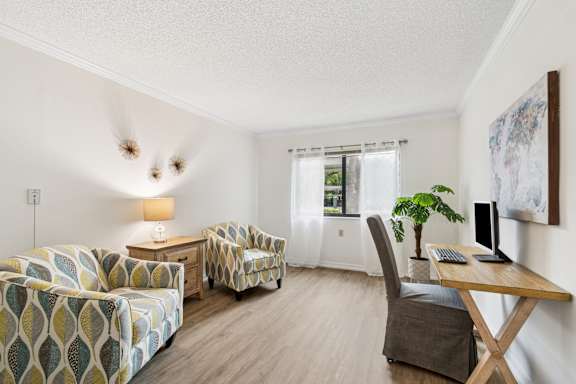 A living room with a couch, chair, and desk at Hampton Apartments, Florida