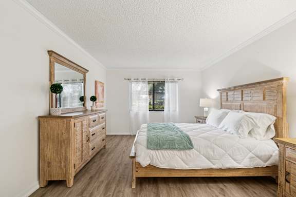 A bedroom with a large bed, a dresser, and a mirror at Hampton Apartments, Clearwater, Florida