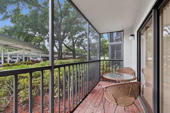 A balcony with a table and chairs overlooking a parking lot at Hampton Apartments, Clearwater