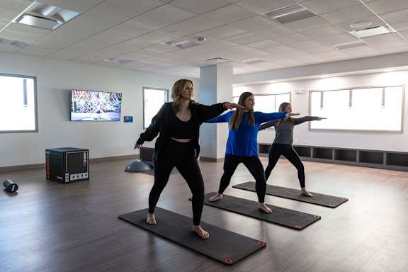 three women standing on yoga mats in a yoga studio at The Residences at Tesson Ridge, Saint Louis, Missouri
