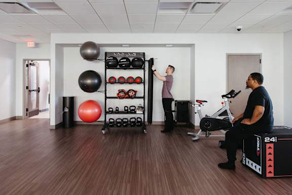 two people in a fitness room with weights and exercise equipment at The Residences at Tesson Ridge, Saint Louis