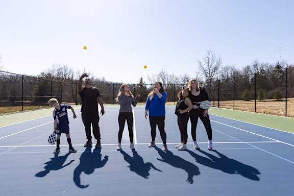 a group of people on a tennis court with tennis balls at The Residences at Tesson Ridge, Saint Louis, MO, 63128