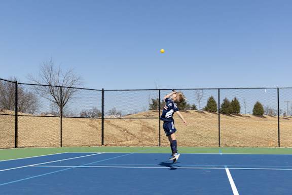 a young boy jumping to hit a tennis ball on a tennis court at The Residences at Tesson Ridge, Missouri, 63128